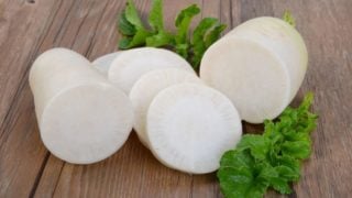 Close-up of freshly sliced daikon with leaves on a wooden table