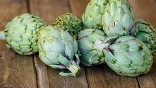 A closeup view of fresh artichokes on a wooden table