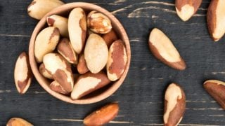 A bowl filled with Brazil nuts on a wooden background