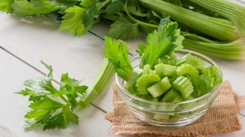 Celery stalks next to a bowl with sliced celery