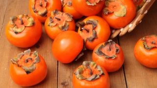 Close up of fresh and tasty orange persimmons on a wooden table