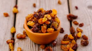 A small bowl of raisins on a wooden table