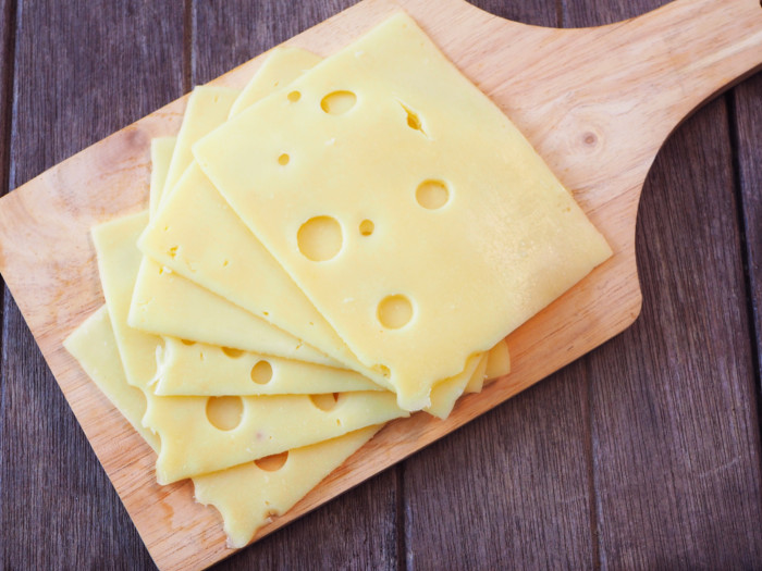  Flatlay immagine di una tavola di formaggio con fette di formaggio su una superficie di legno. 