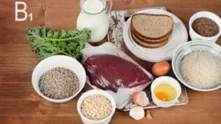 Foods rich in vitamin B1 or thiamin (Milk, bread, beef, eggs, rice, oats, seeds, legumes) on a wooden table